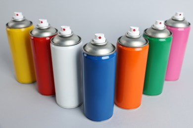 Photo of Colorful cans of spray paints on light grey background