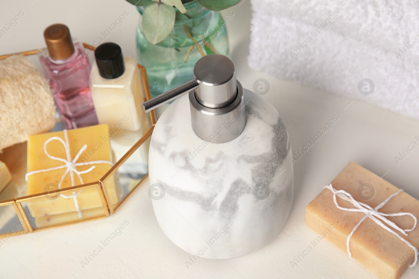 Photo of Marble soap dispenser and toiletries on white table