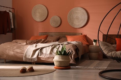 Bed with orange and brown linens in stylish room interior