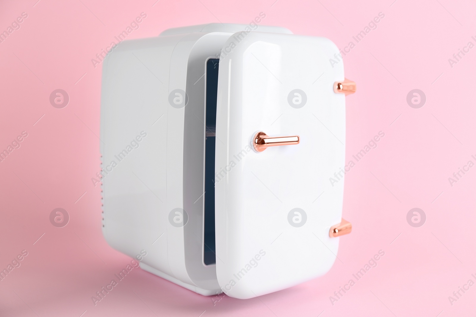 Photo of Mini refrigerator for cosmetics on pink background