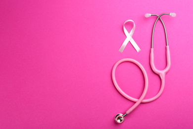 Pink ribbon as breast cancer awareness symbol and stethoscope on color background, flat lay. Space for text