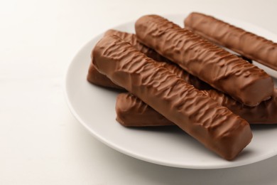 Photo of Sweet tasty chocolate bars on white table, closeup