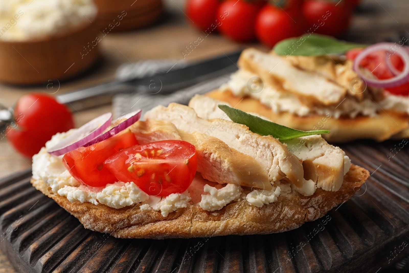 Photo of Board with delicious chicken bruschettas on table, closeup