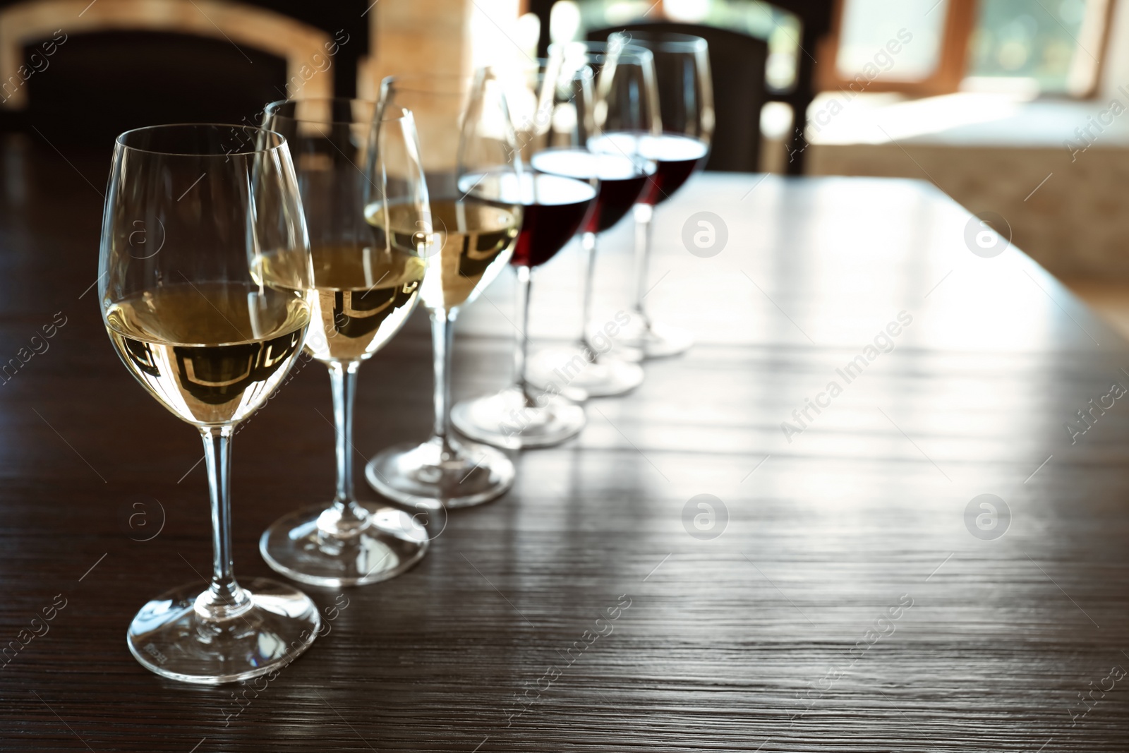 Photo of Glasses of white and red wines on wooden table