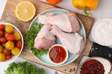 Photo of Flat lay composition with marinade and raw chicken drumsticks on white tiled table