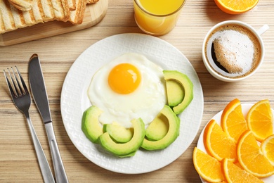 Photo of Delicious breakfast with fried egg served on wooden table, flat lay