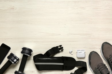 Flat lay composition with black waist bag on white wooden table, space for text