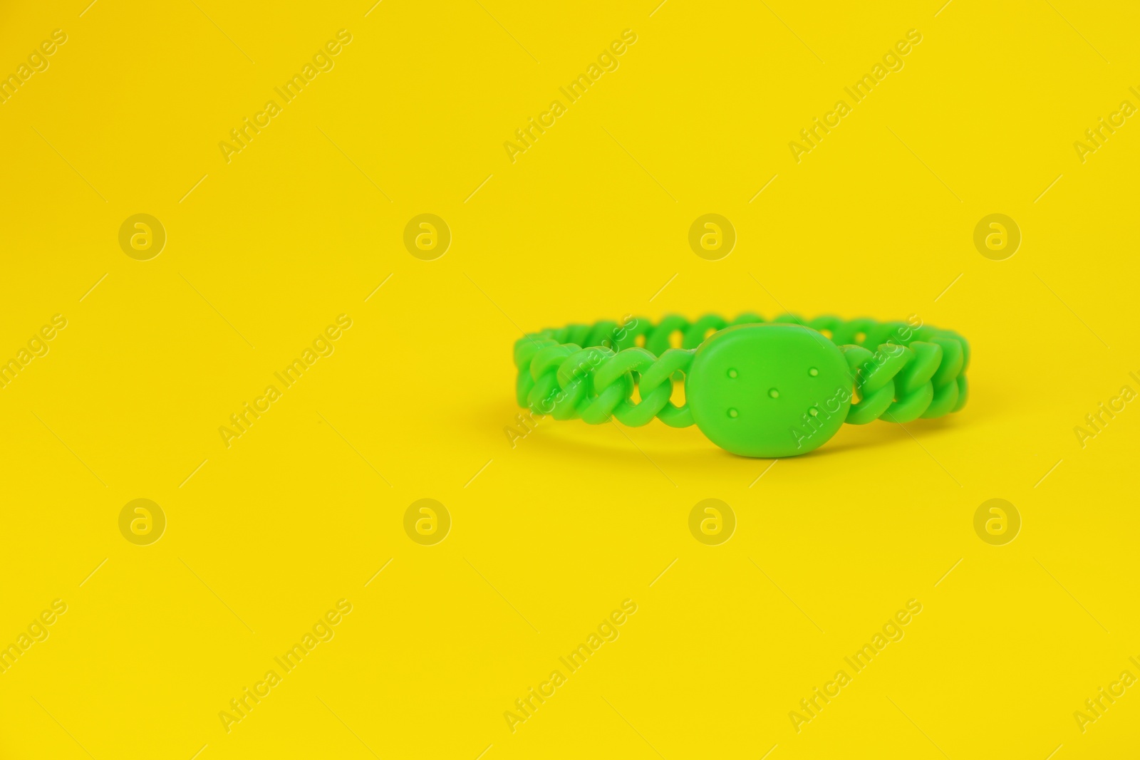 Photo of Insect repellent wrist band on yellow background, space for text
