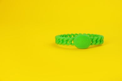 Photo of Insect repellent wrist band on yellow background, space for text