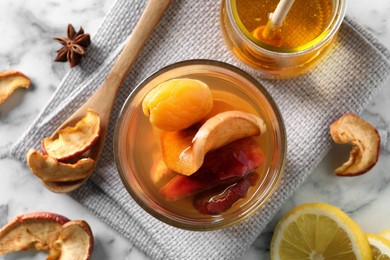 Delicious compote with dried fruits in glass on white marble table, flat lay