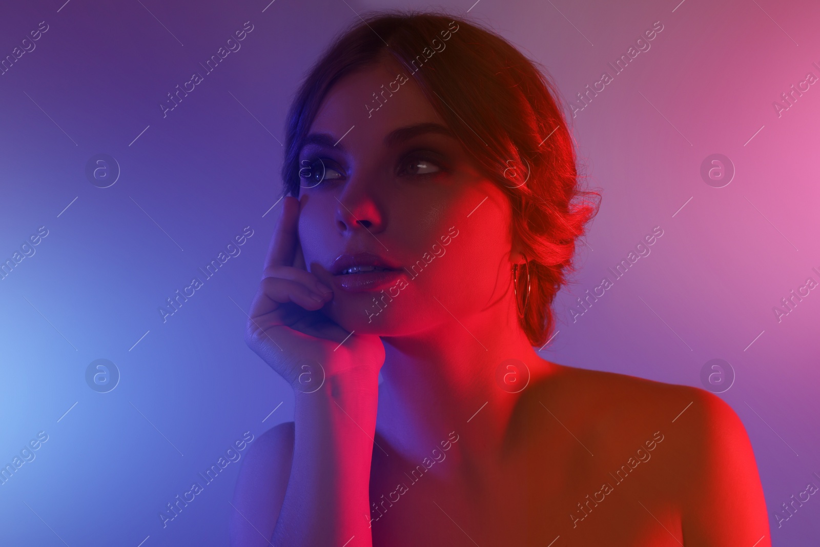 Photo of Fashionable portrait in neon lights. Beautiful young woman posing on purple background