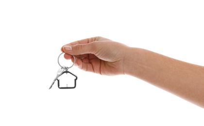 Real estate agent holding house key with trinket on white background, closeup