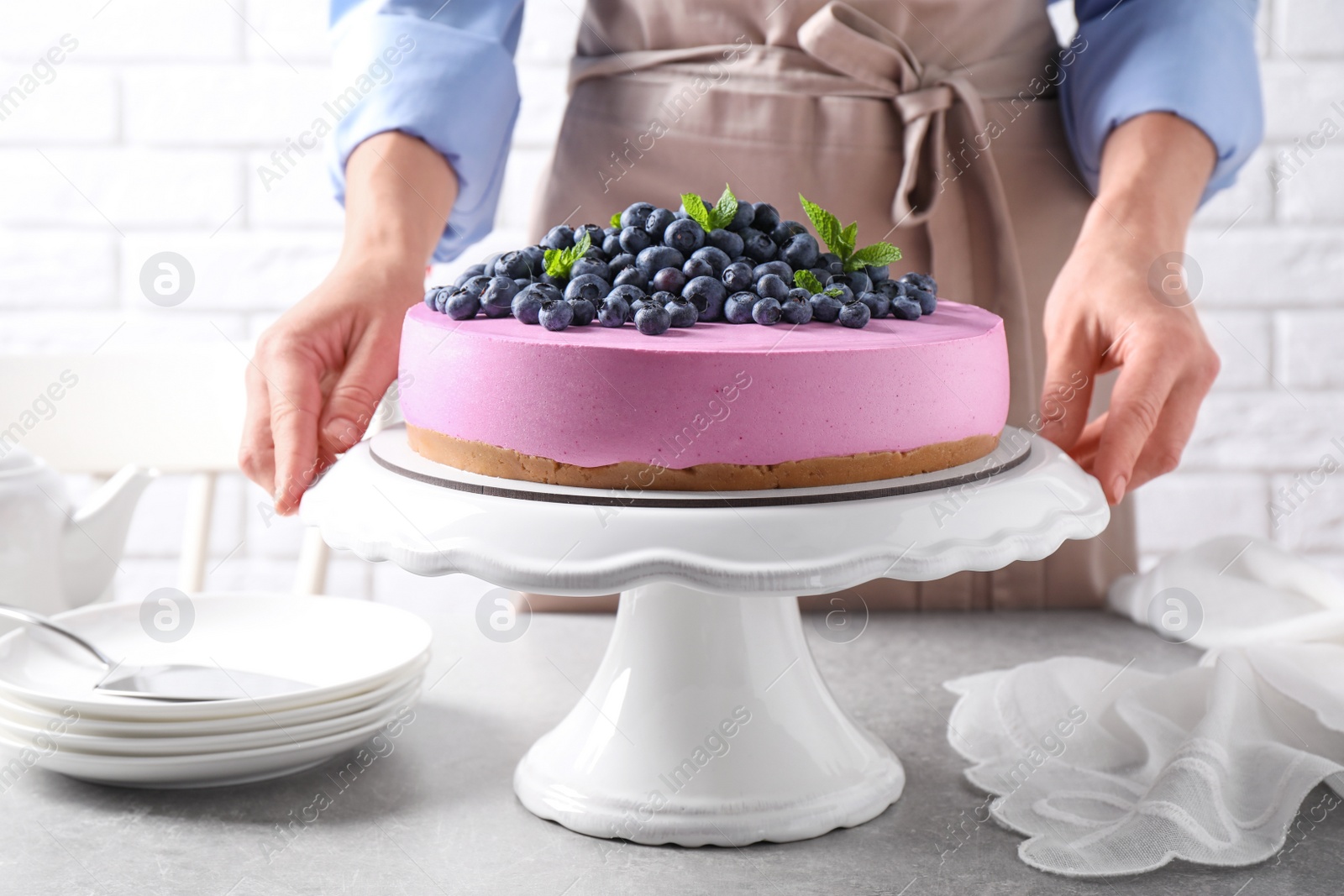 Photo of Young woman with tasty blueberry cake at grey table, closeup