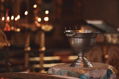 Photo of Silver vessel with holy water on stand in church, space for text. Baptism ceremony
