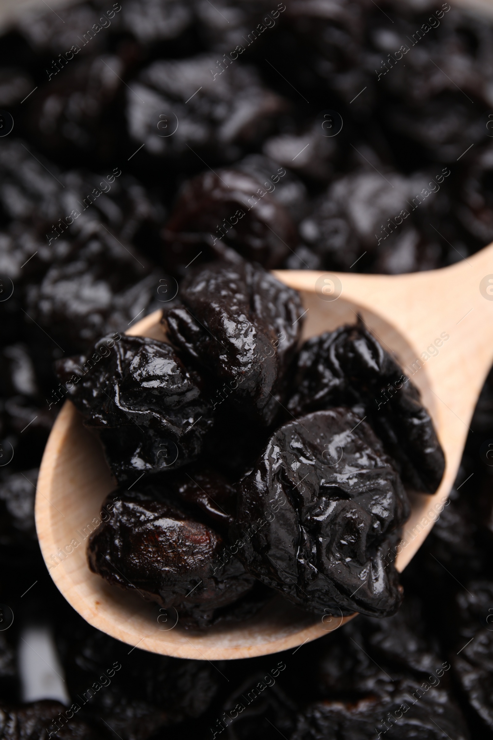 Photo of Pile of sweet dried prunes and spoon, closeup