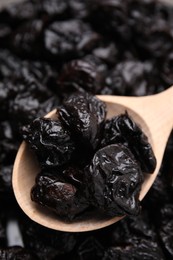 Pile of sweet dried prunes and spoon, closeup