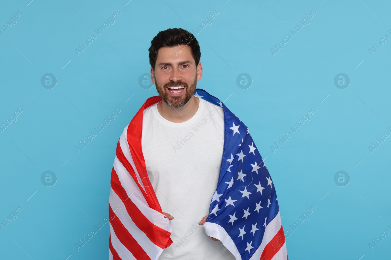 Photo of 4th of July - Independence Day of USA. Happy man with American flag on light blue background