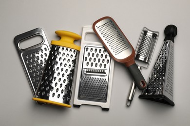Photo of Different modern graters on grey background, flat lay