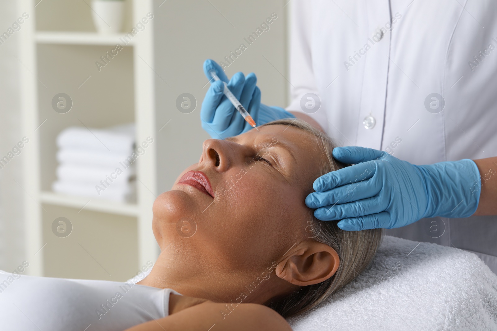 Photo of Doctor giving facial injection to senior woman in clinic, closeup. Cosmetic surgery