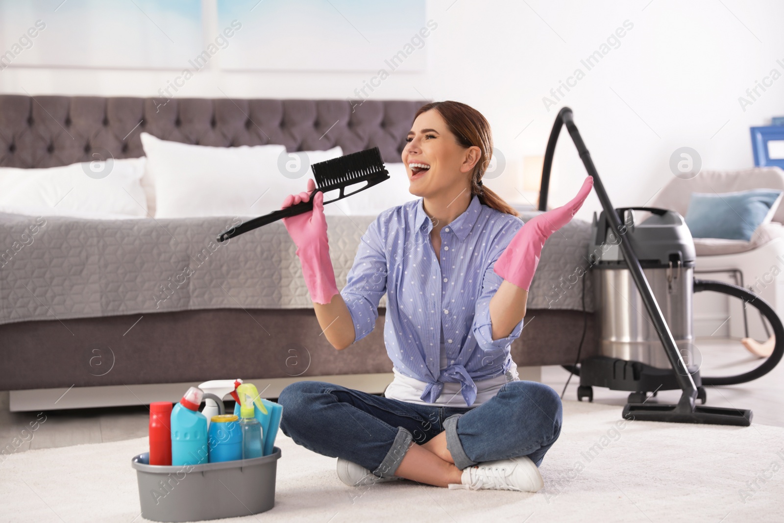 Photo of Happy woman having fun while cleaning bedroom