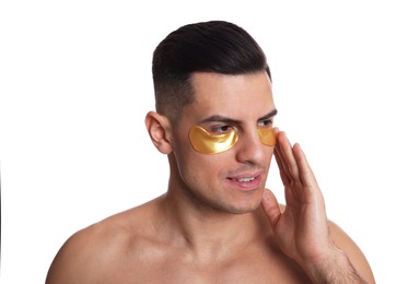 Man applying golden under eye patch on white background