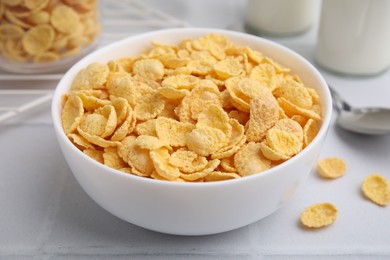 Photo of Tasty crispy corn flakes in bowl on white table, closeup. Breakfast cereal