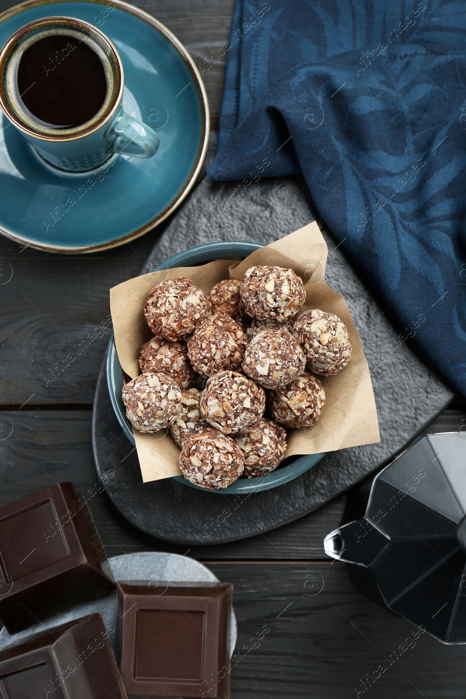 Photo of Delicious sweet chocolate candies, bars and coffee on black wooden table, flat lay