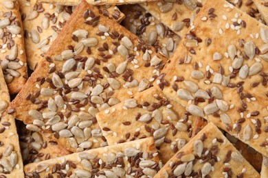 Photo of Cereal crackers with flax, sunflower and sesame seeds as background, top view