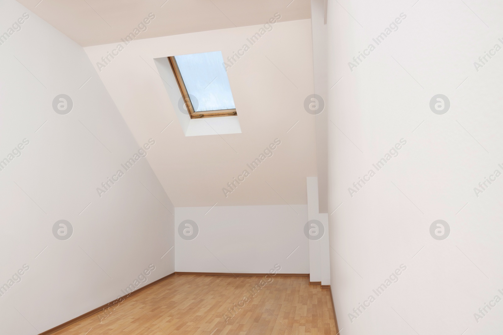 Photo of Light spacious attic room with window on slanted ceiling