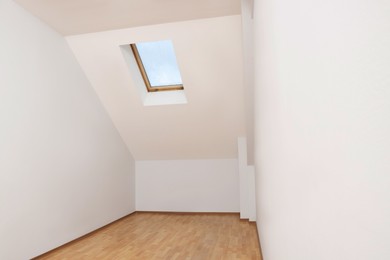 Light spacious attic room with window on slanted ceiling