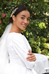 Young bride wearing beautiful wedding dress in park 