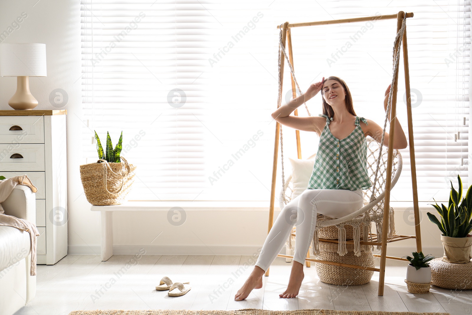 Photo of Beautiful woman resting in hammock chair at home