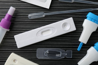 Photo of Disposable express test kits on black wooden table, flat lay