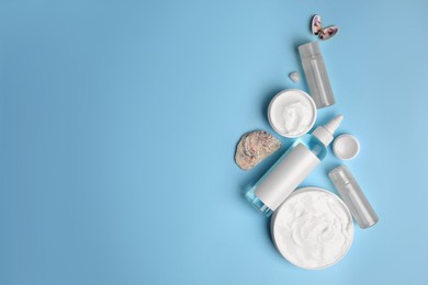 Flat lay composition with different cosmetic products on light blue background. Space for text