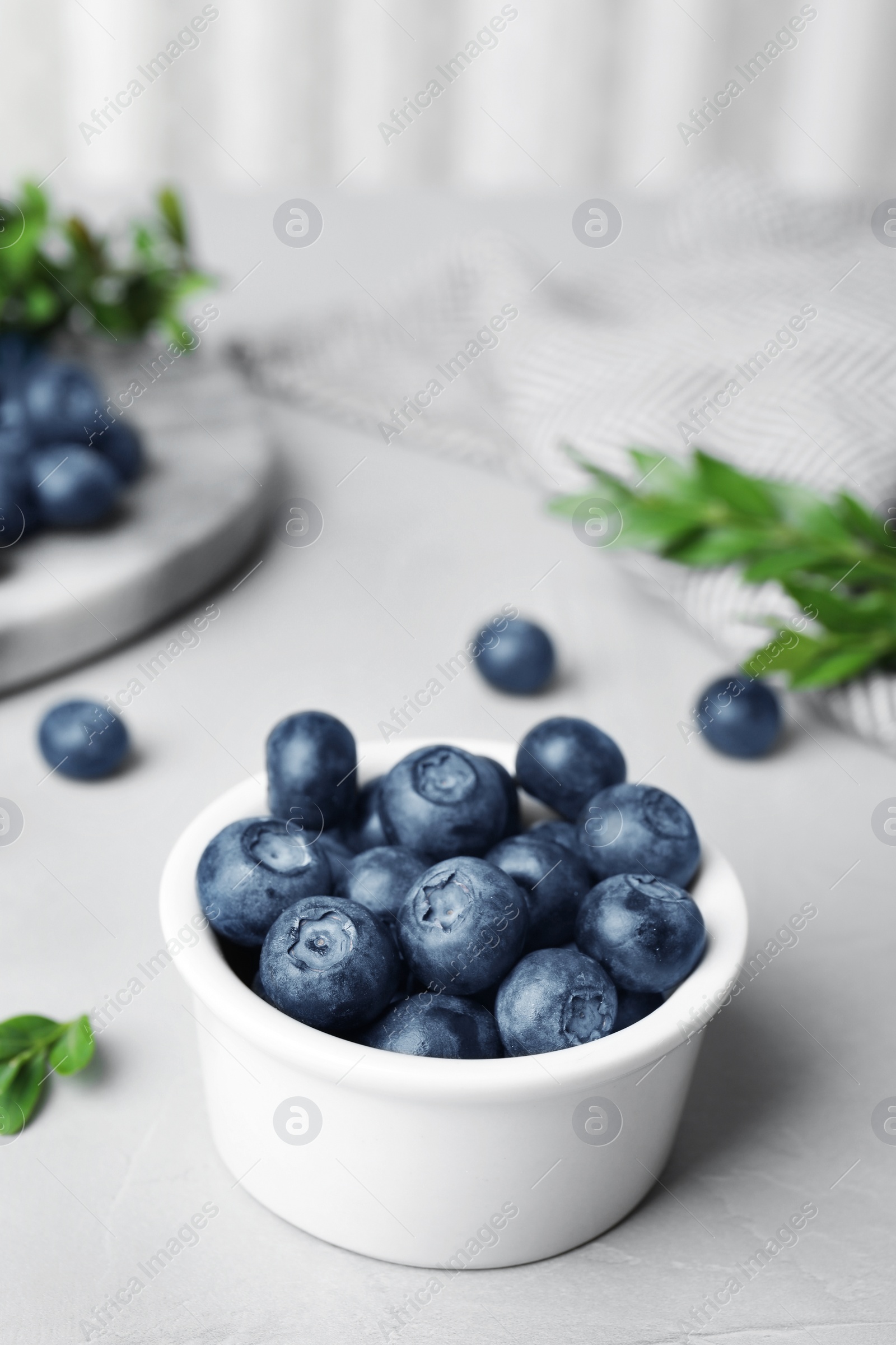 Photo of Bowl of tasty blueberries on grey table, space for text