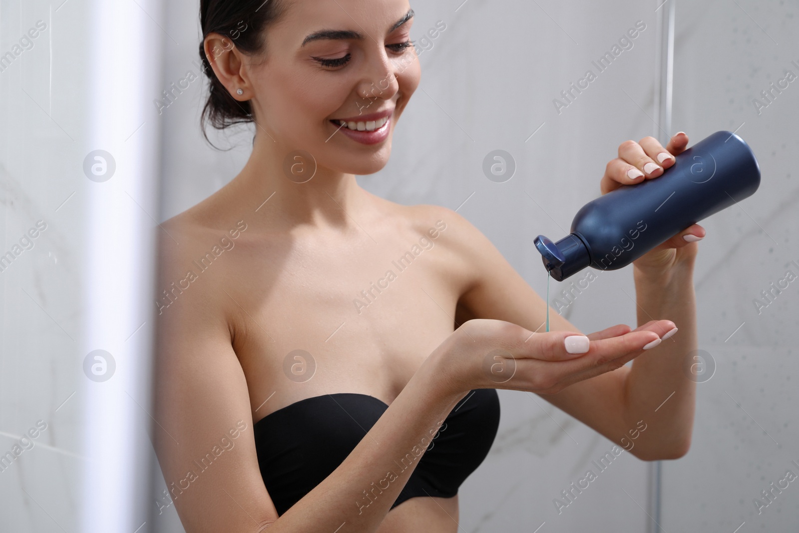 Photo of Young woman using gel in shower at home