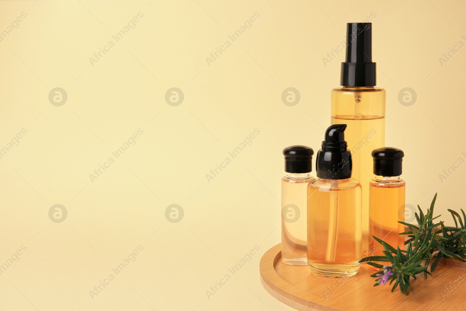 Photo of Bottles with cosmetic products and rosemary on beige background. Space for text