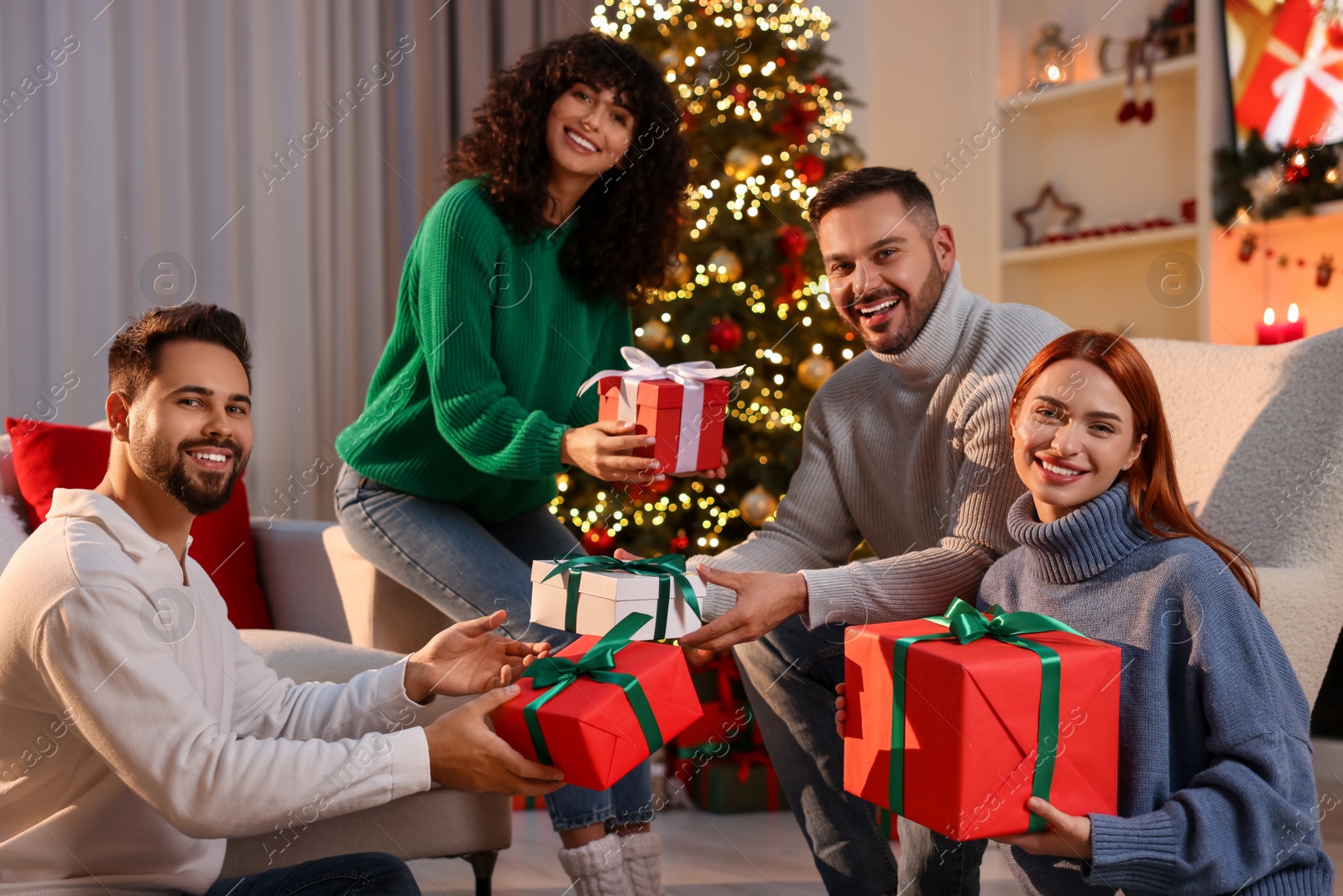 Photo of Christmas celebration. Happy friends exchanging gifts at home