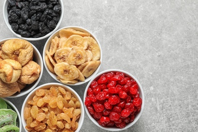 Photo of Bowls of different dried fruits on grey background, top view with space for text. Healthy food