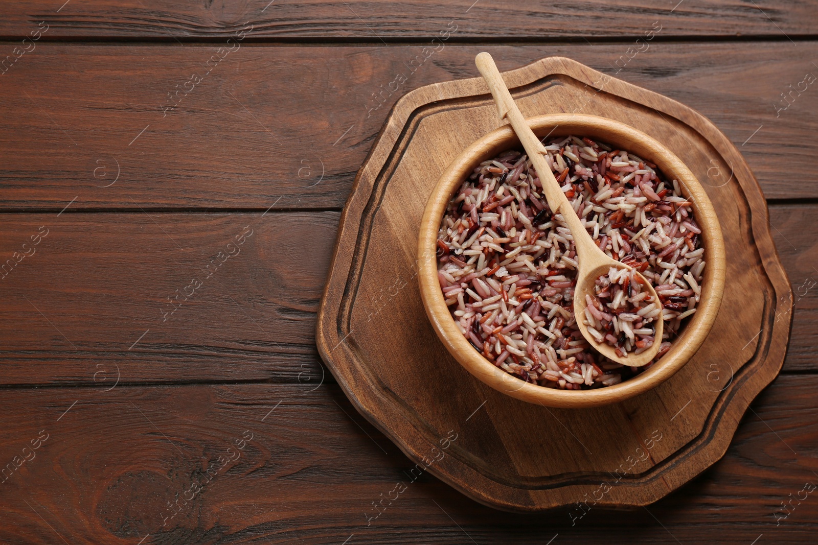 Photo of Delicious brown rice served on wooden table, top view. Space for text