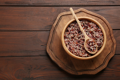 Photo of Delicious brown rice served on wooden table, top view. Space for text