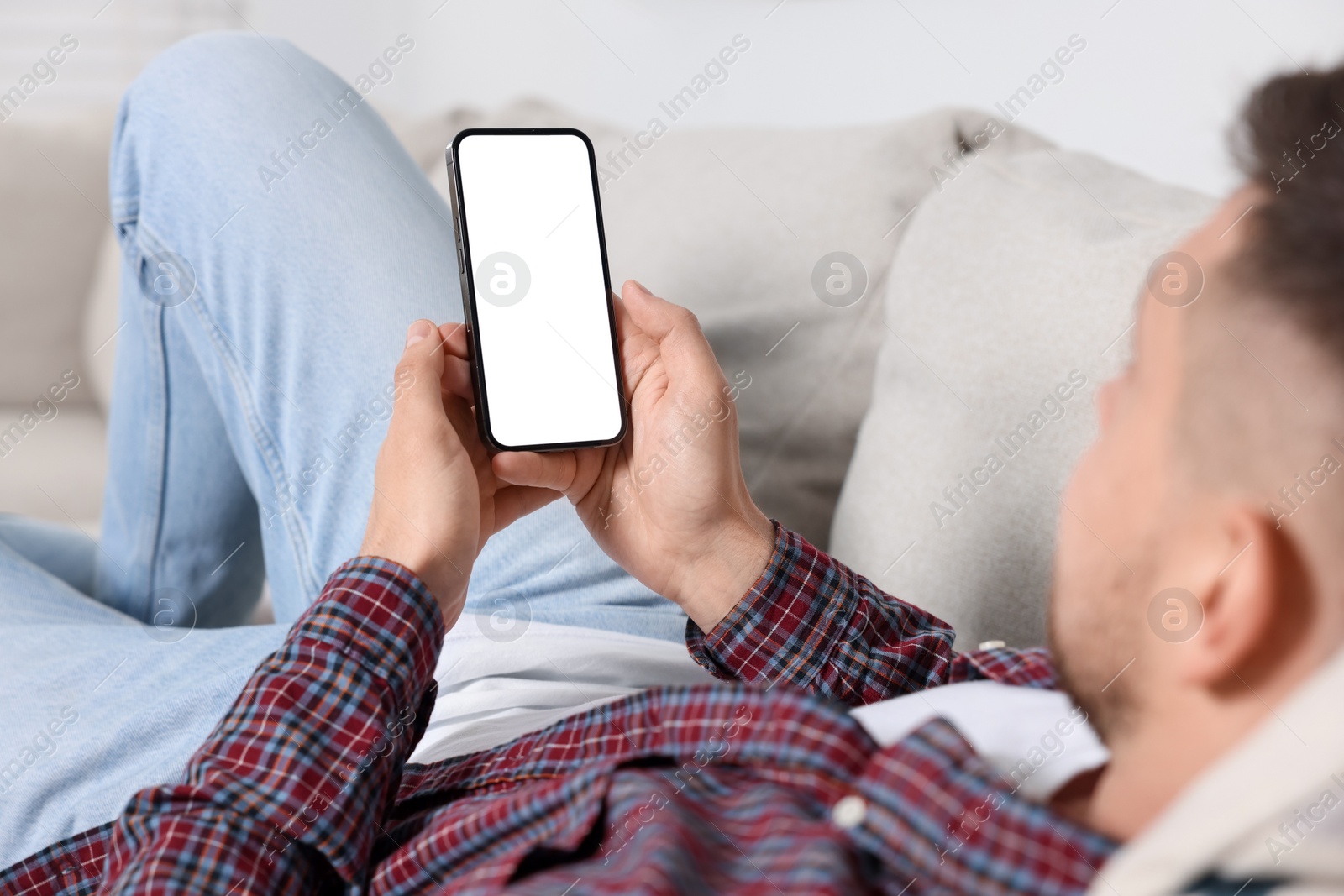 Photo of Man using mobile phone on sofa at home, closeup