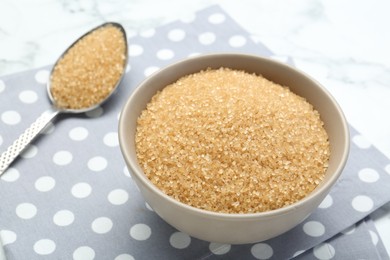 Photo of Brown sugar in bowl and spoon on table, closeup