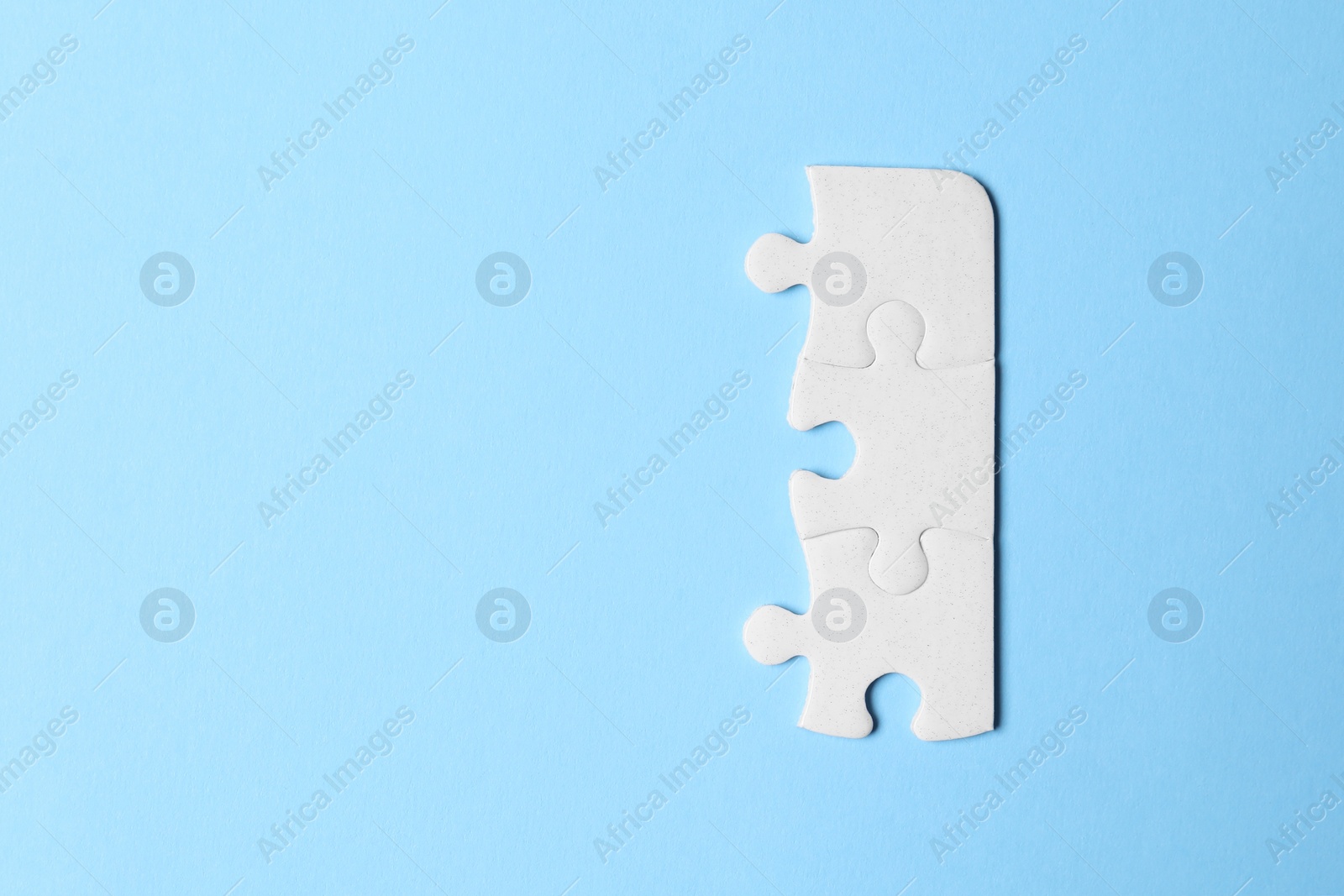 Photo of Blank white puzzle pieces on light blue background, flat lay. Space for text