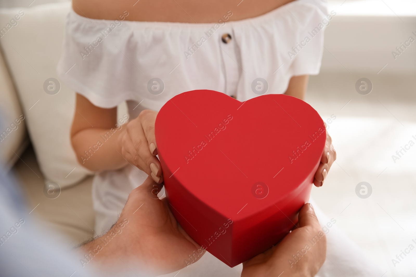 Photo of Lovely couple with gift box at home, closeup. Valentine's day celebration