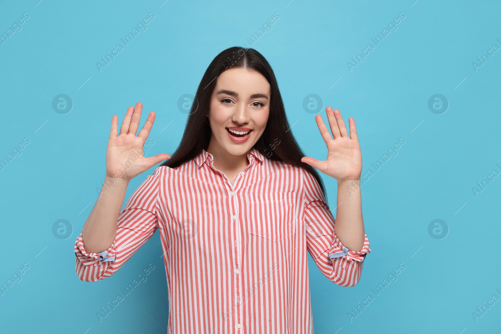 Photo of Happy woman giving high five with both hands on light blue background