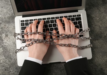 Photo of Man chained to laptop at grey table, top view. Internet addiction