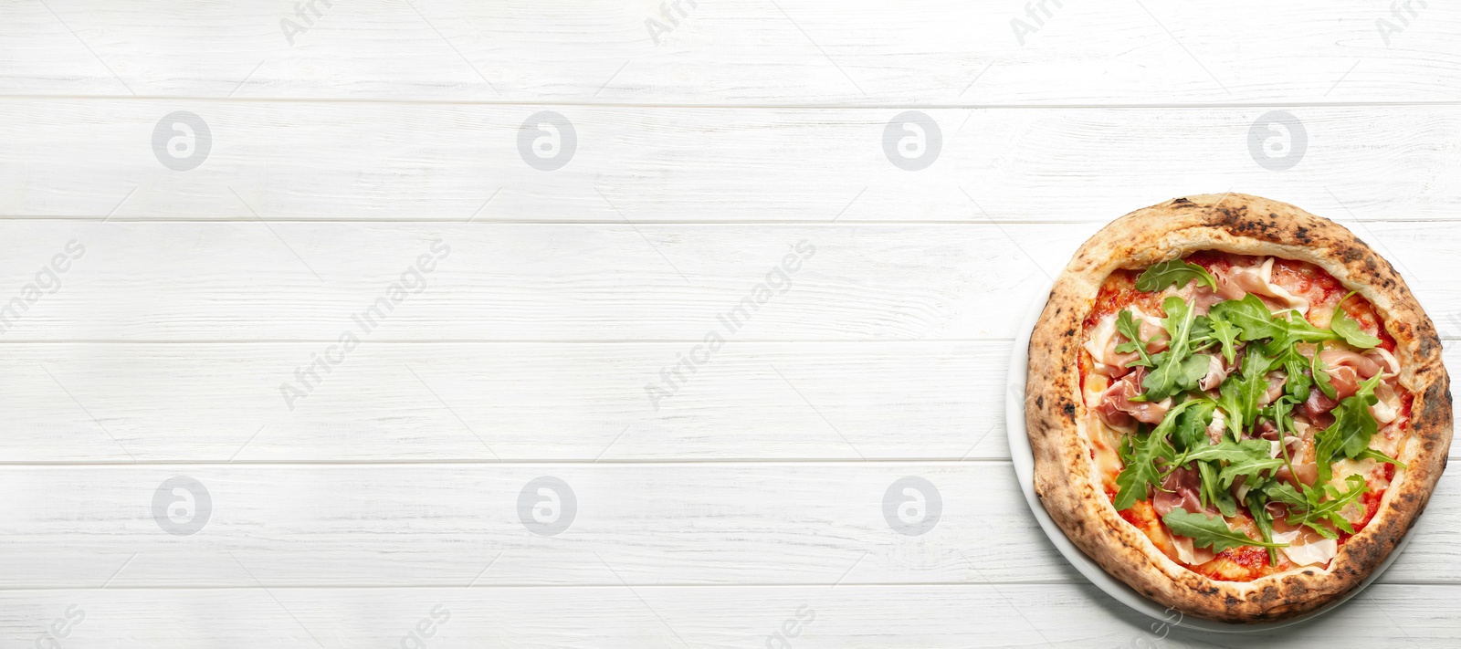 Image of Tasty pizza with meat and arugula on white wooden table, top view with space for text. Banner design