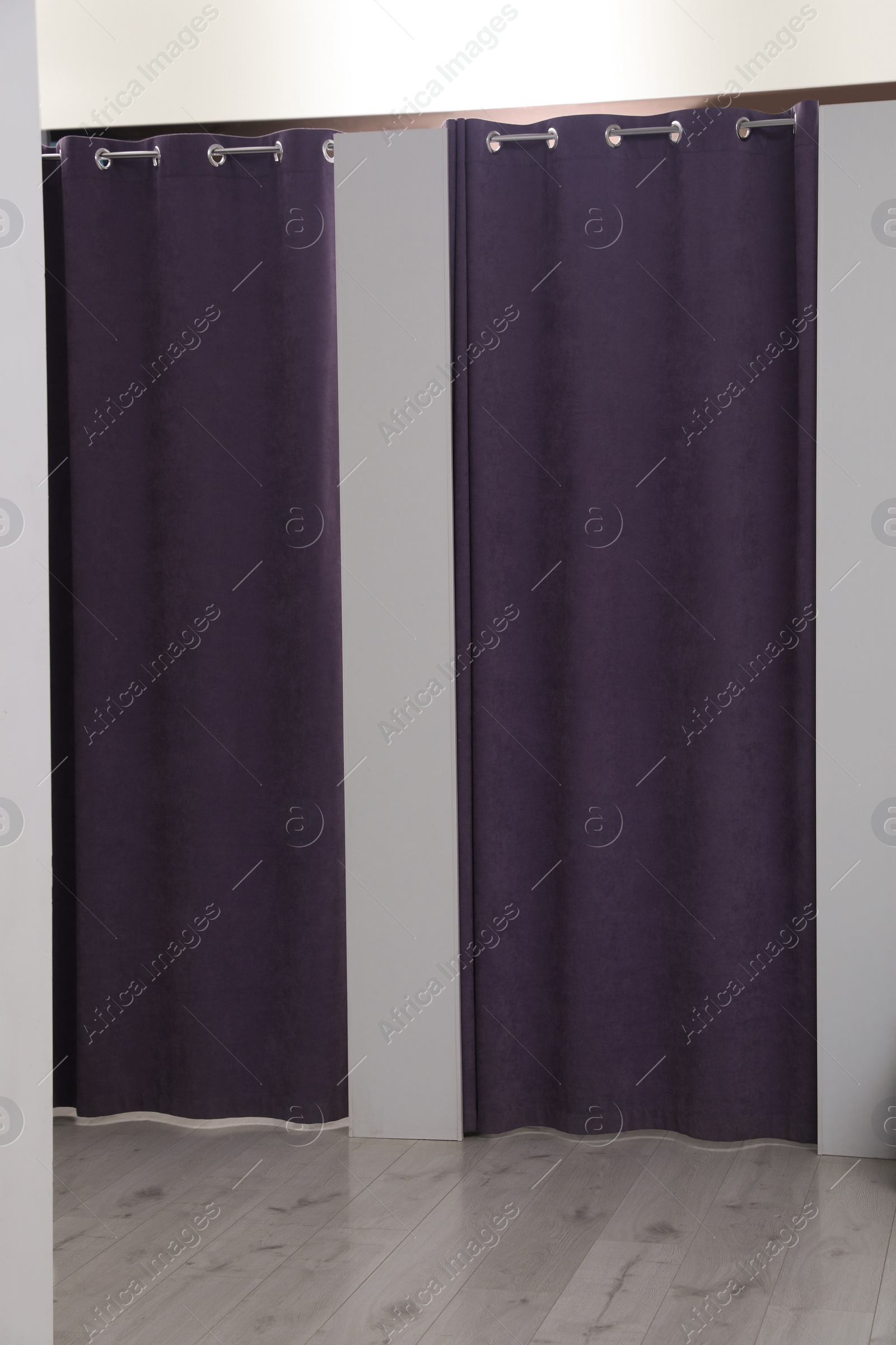 Photo of Dressing rooms with stylish purple curtains in fashion store