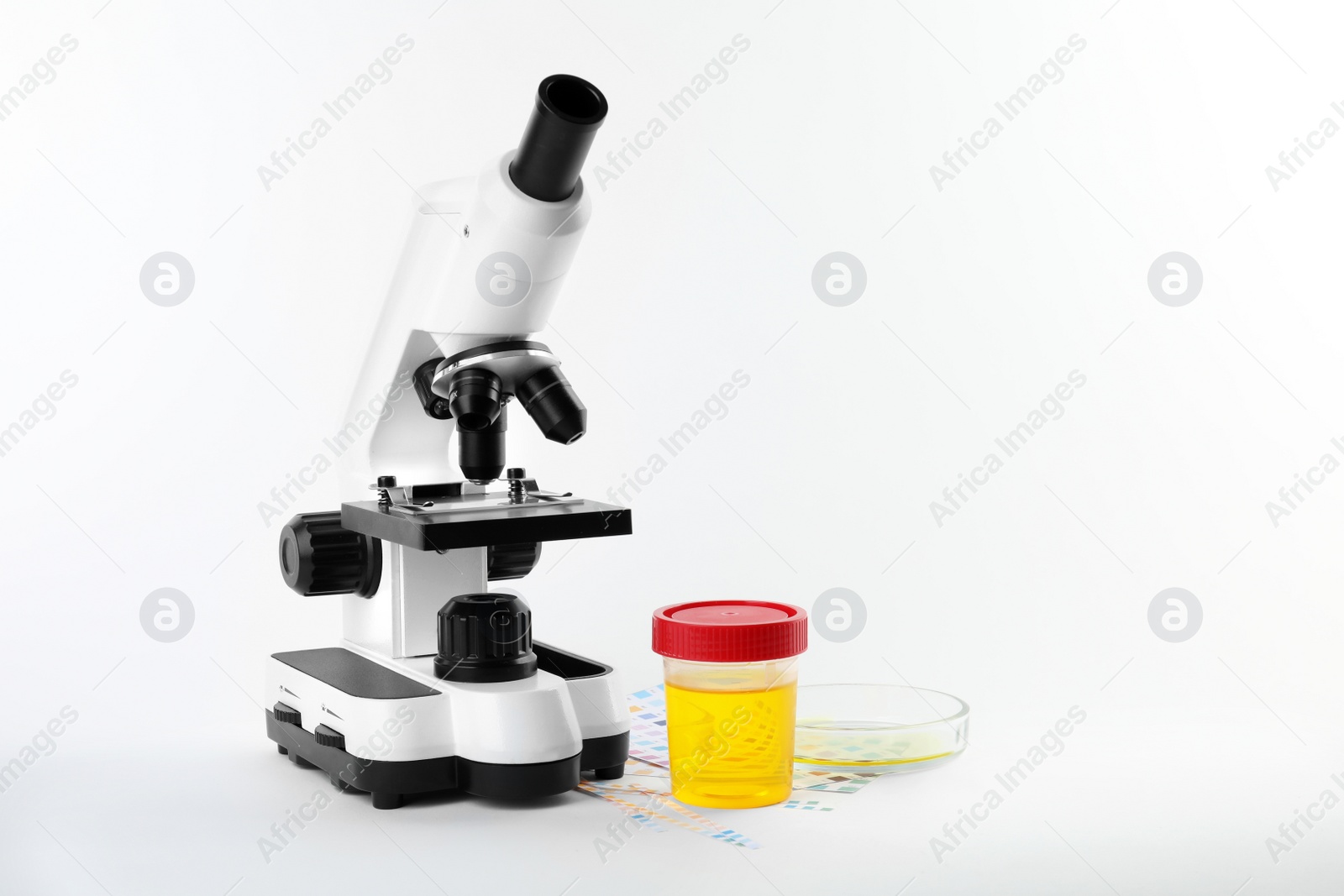 Photo of Laboratory ware with urine samples for analysis and microscope on white background